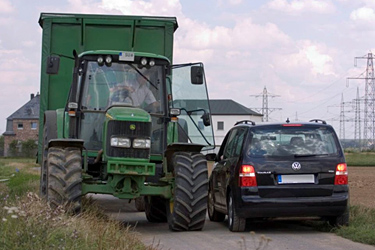 Schlepper und Auto auf einem Wirtschaftsweg