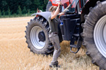 Landwirtin steigt auf einen Schlepper. Foto: Christian Mühlhauen, landpixel.de